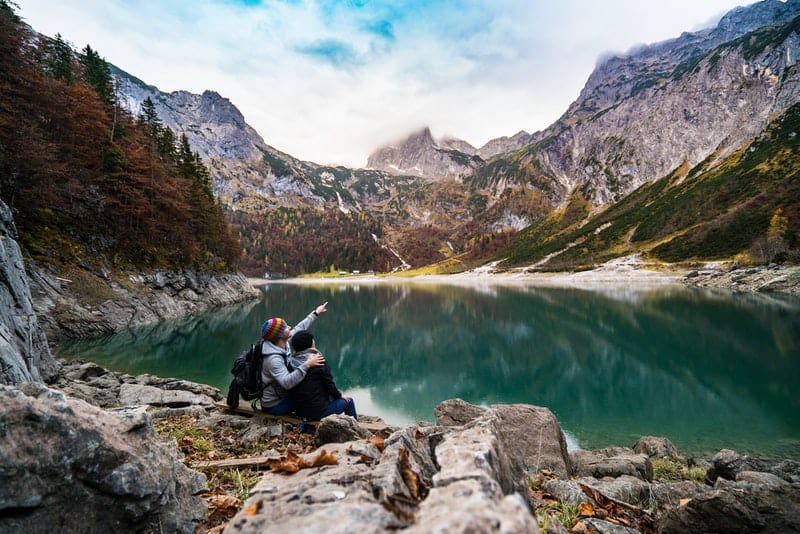 un couple aimant est assis sur une montagne au bord du lac