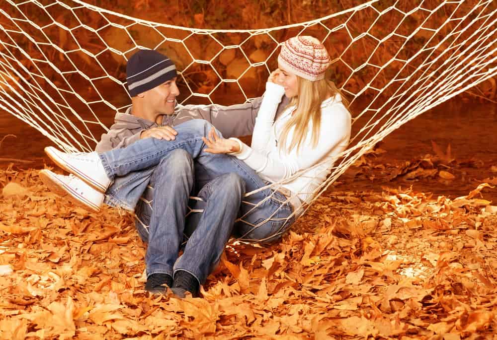 un couple amoureux assis dans un filet au-dessus des feuilles et de parler