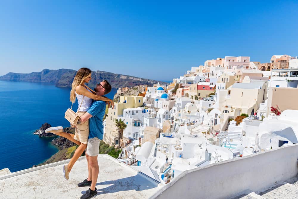 un couple d'amoureux debout dans une étreinte sur une terrasse donnant sur la mer et la ville