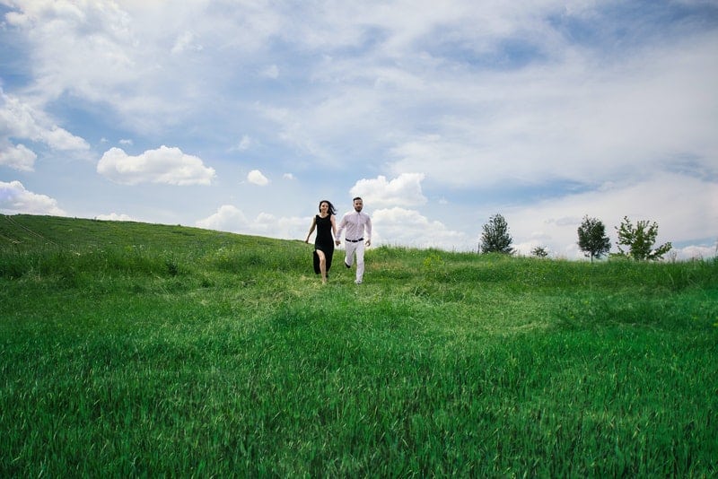 un couple d'amoureux heureux traverse un champ d'herbe