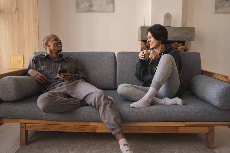 un couple souriant assis sur un canapé et boire du café