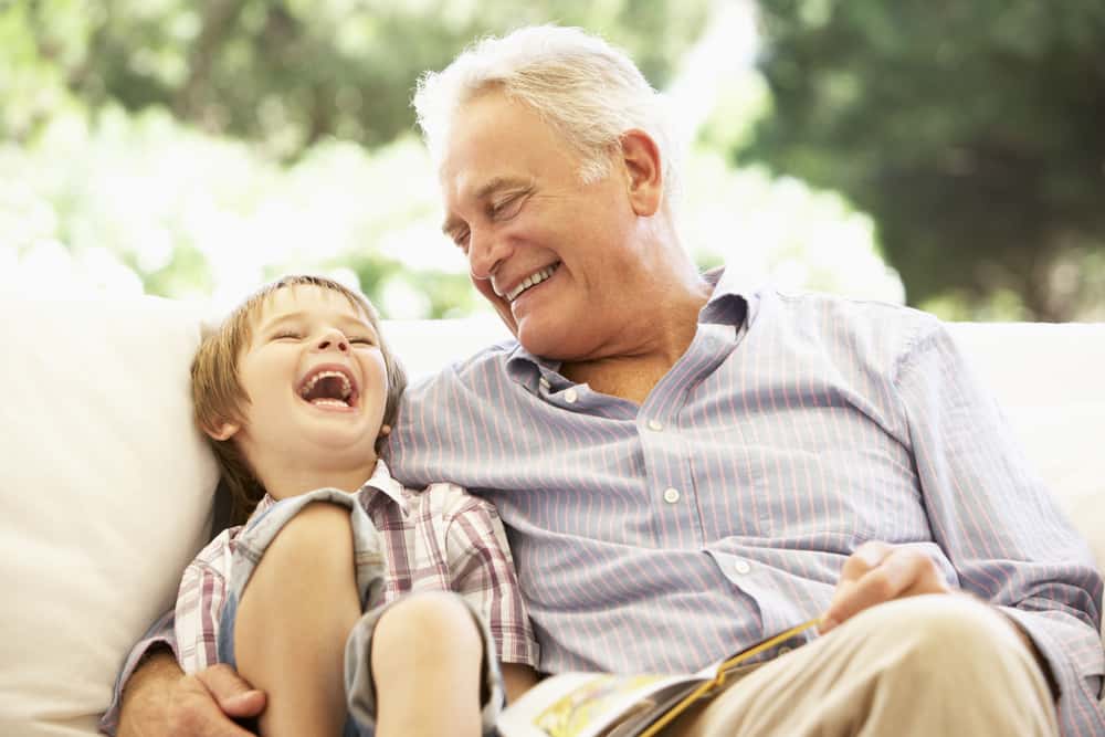 un grand-père et un petit-fils souriants sont assis dans un fauteuil
