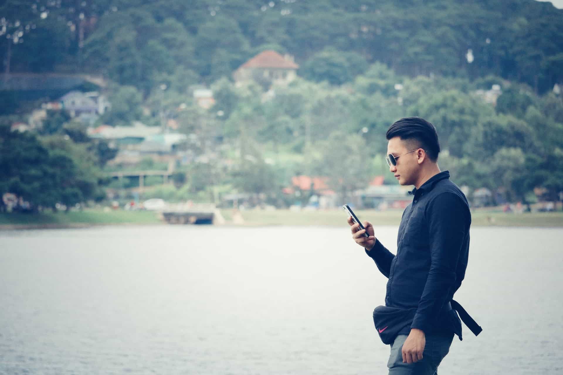 un homme avec un téléphone à la main au bord de la rivière