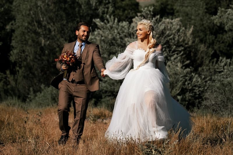 un homme avec une femme tient la main et court alors qu'elle est en robe de mariée