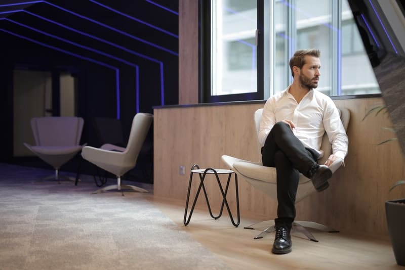 un homme en chemise blanche est assis près de la fenêtre
