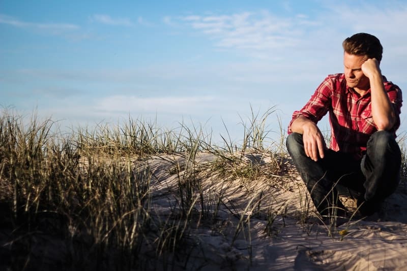 un homme en chemise rouge est assis seul à l'extérieur