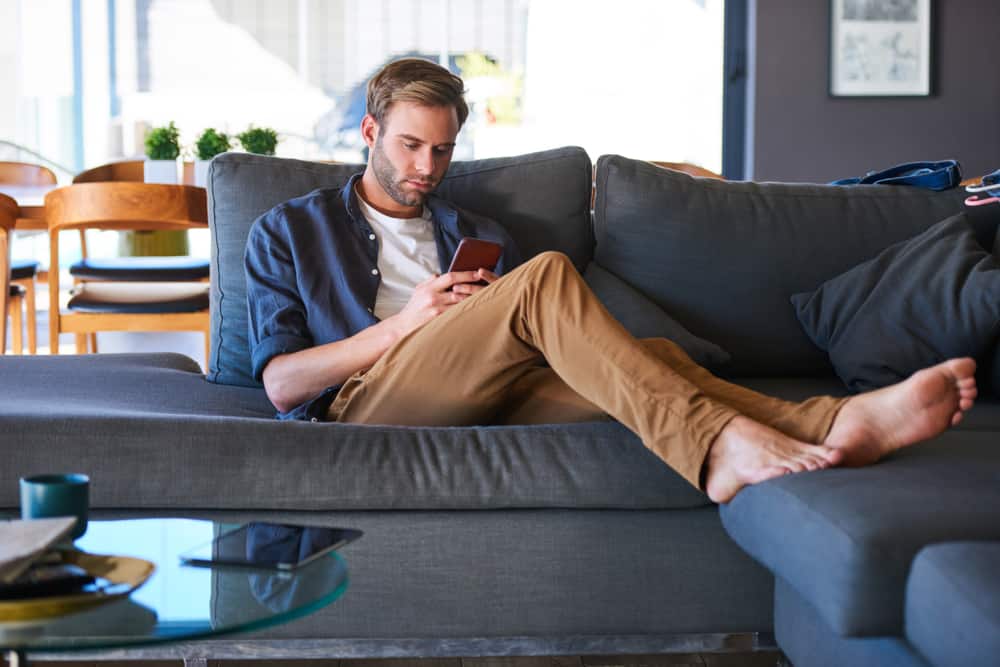 un homme est assis sur un journal et écrit un sms