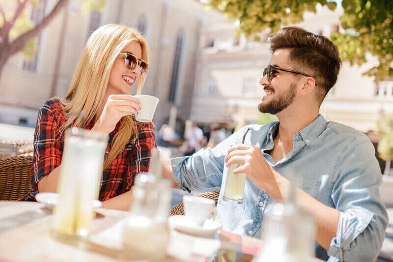 un homme et une femme avec des lunettes s'asseoir et boire du café