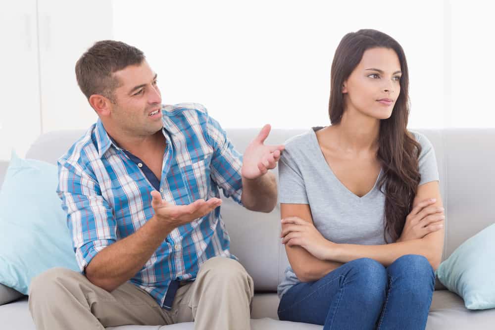un homme et une femme en querelle sont assis sur le canapé