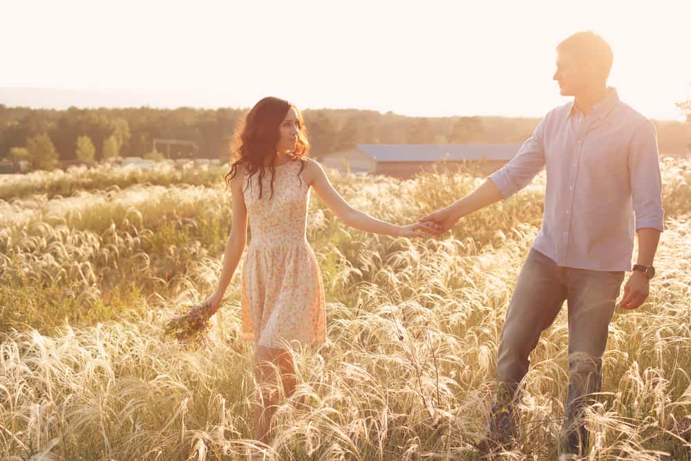 un homme et une femme marchent dans un champ de blé