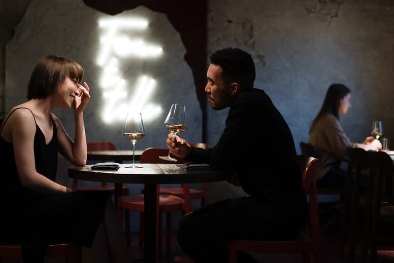 un homme et une femme s'assoient à une table et boivent du vin