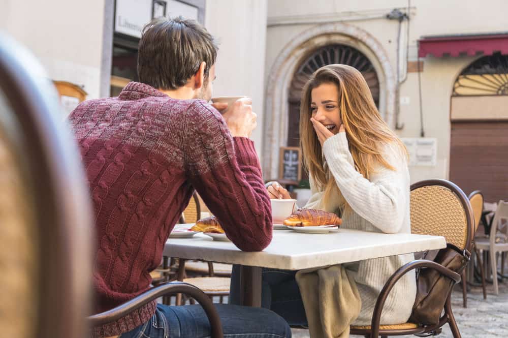 un homme et une femme s'assoient à une table et rient