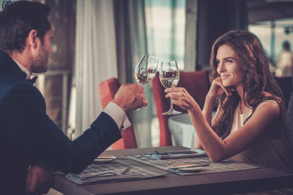 un homme et une femme se regardent pendant qu'ils portent un toast