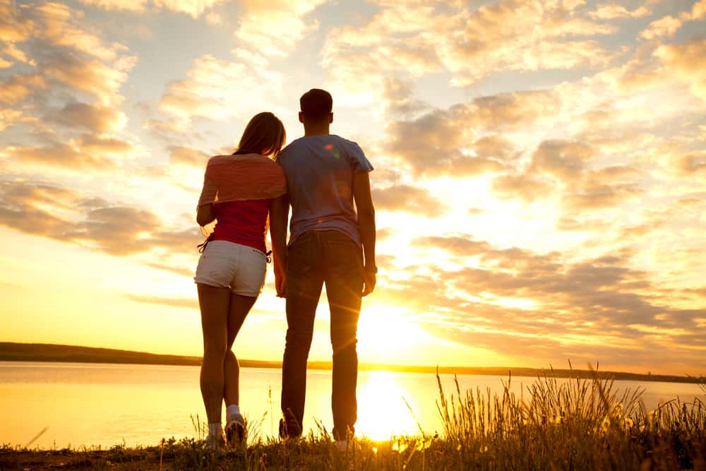 un homme et une femme se tiennent au bord de la rivière