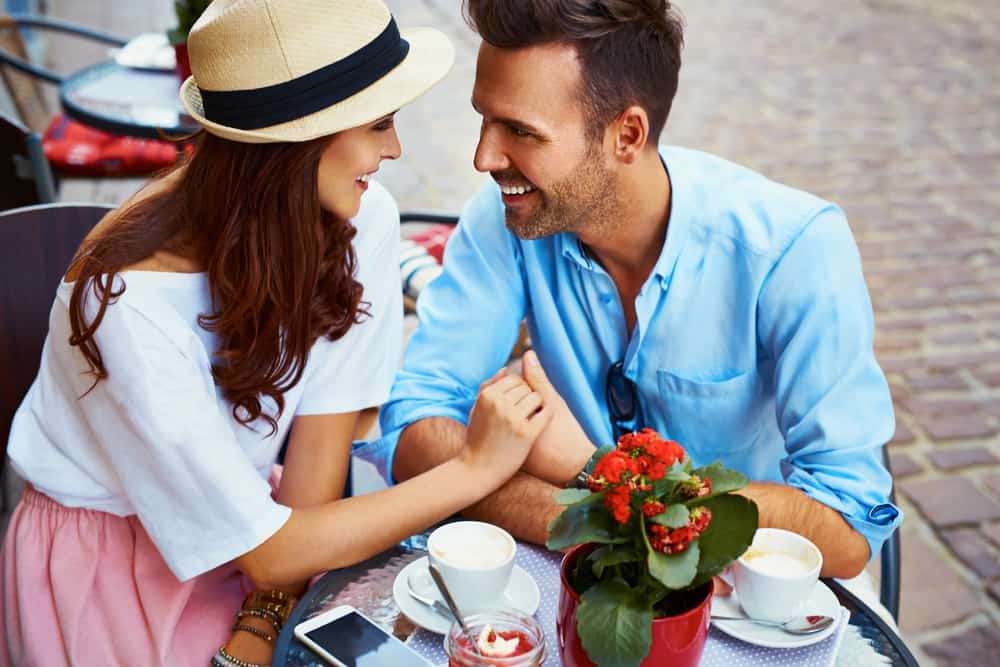 un homme et une femme sont assis à boire du café et à se regarder