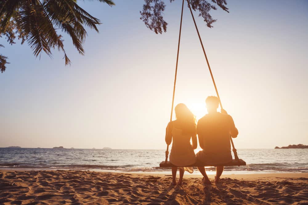 un homme et une femme sont assis ns se balançant au bord de la mer