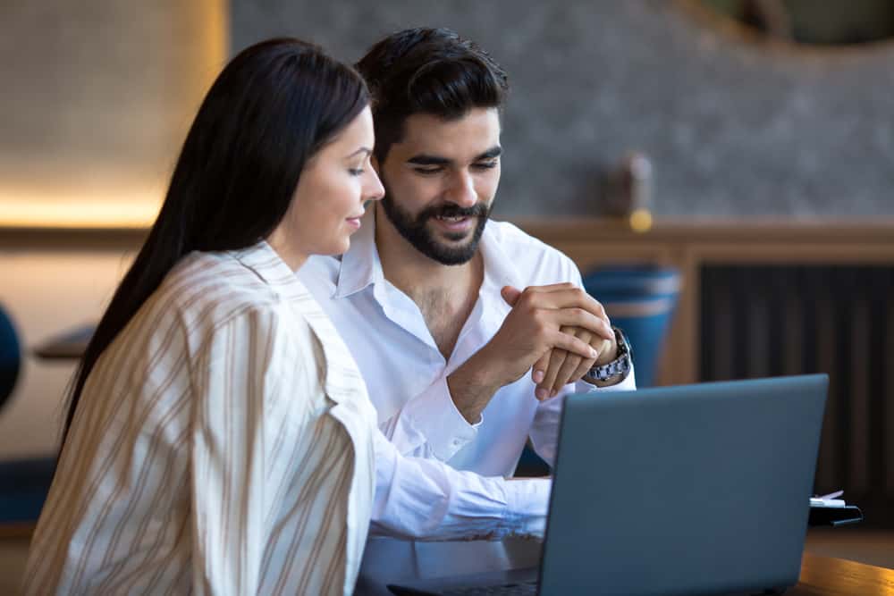 un homme et une femme sont assis à une table pendant qu'il la tient par les bras