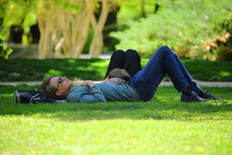 un homme et une femme sont couchés et se reposent dans le parc
