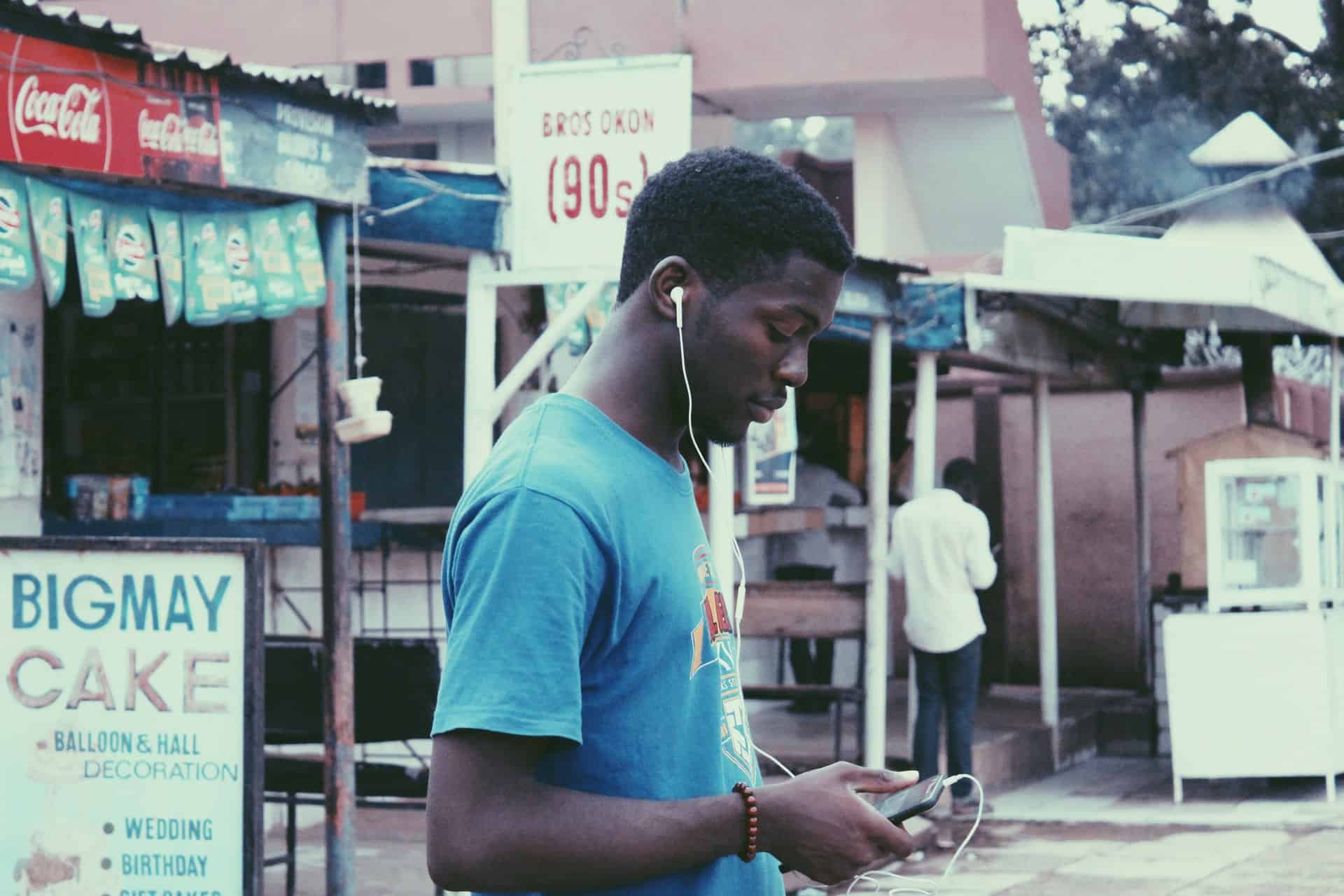 un homme marche dans la rue avec un casque dans ses oreilles et un téléphone à la main