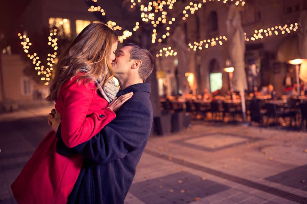 un homme porte une femme et l'embrasse dans la rue