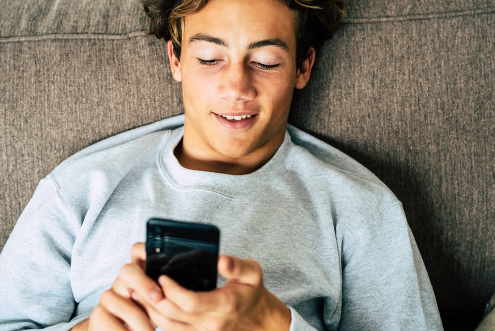 un homme souriant ment et envoie des SMS sur son smartphone