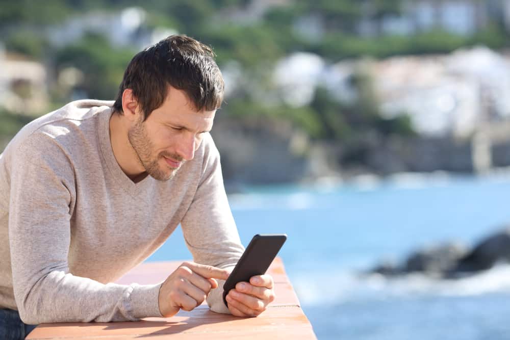 un homme sérieux sur la terrasse est debout et envoie des SMS