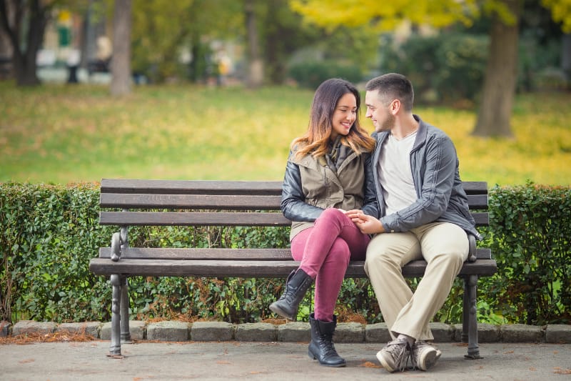 un jeune couple amoureux assis sur un banc de parc