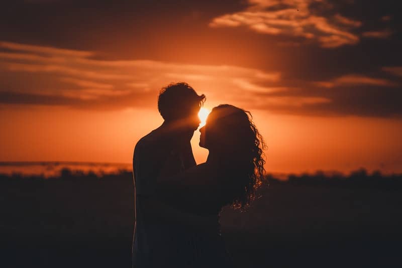 un jeune homme et une fille s'embrassant au coucher du soleil