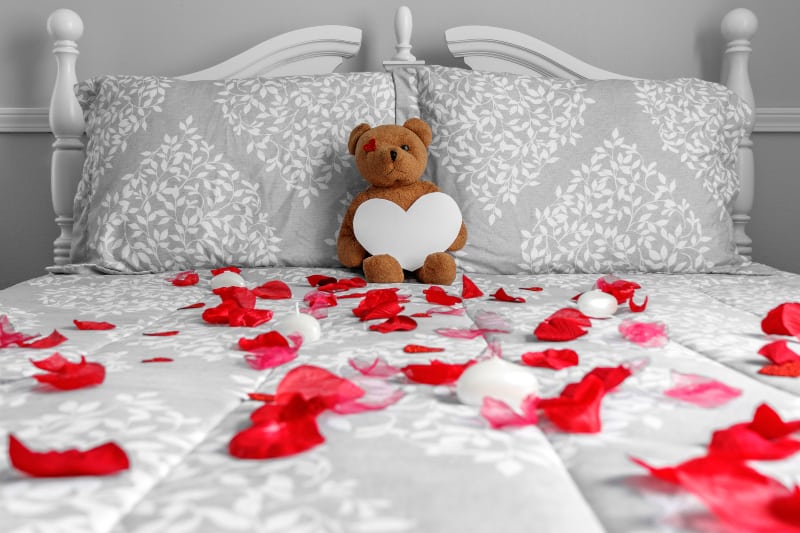 un ours en peluche sur un lit couvert de roses