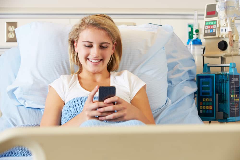 un patient souriant à l'hôpital lit un sms