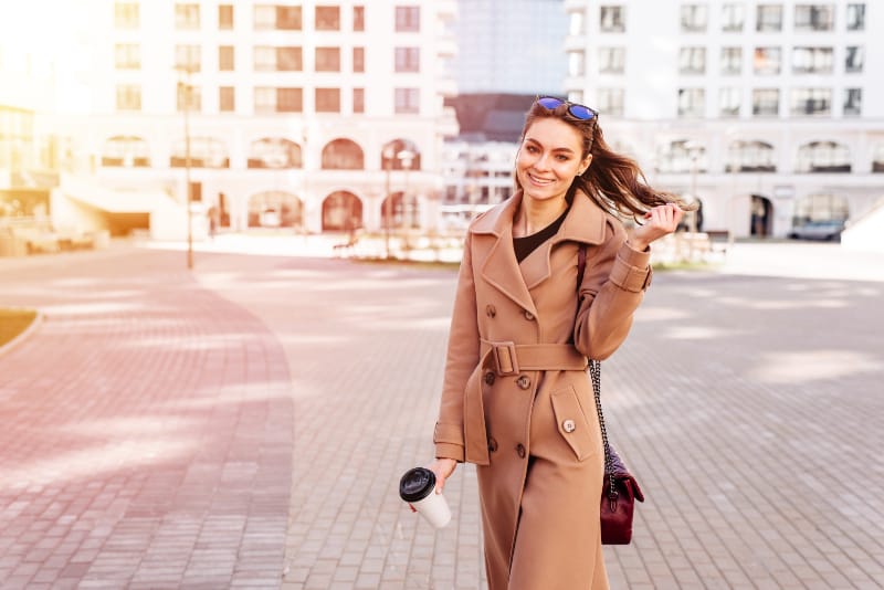 une belle jeune fille dans un manteau se promène dans la ville