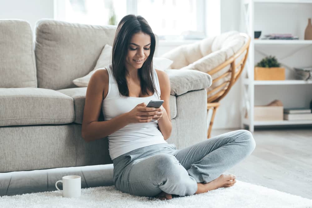 une femme assise sur le sol avec un téléphone et du café