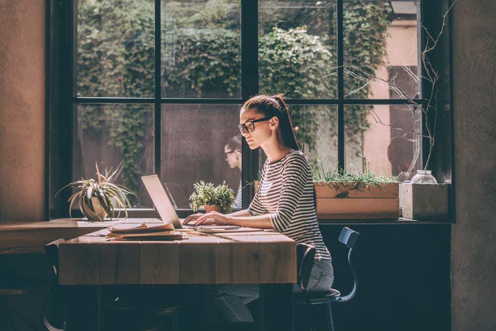 une femme aux cheveux attachés assis à un bureau et travaillant sur un ordinateur portable