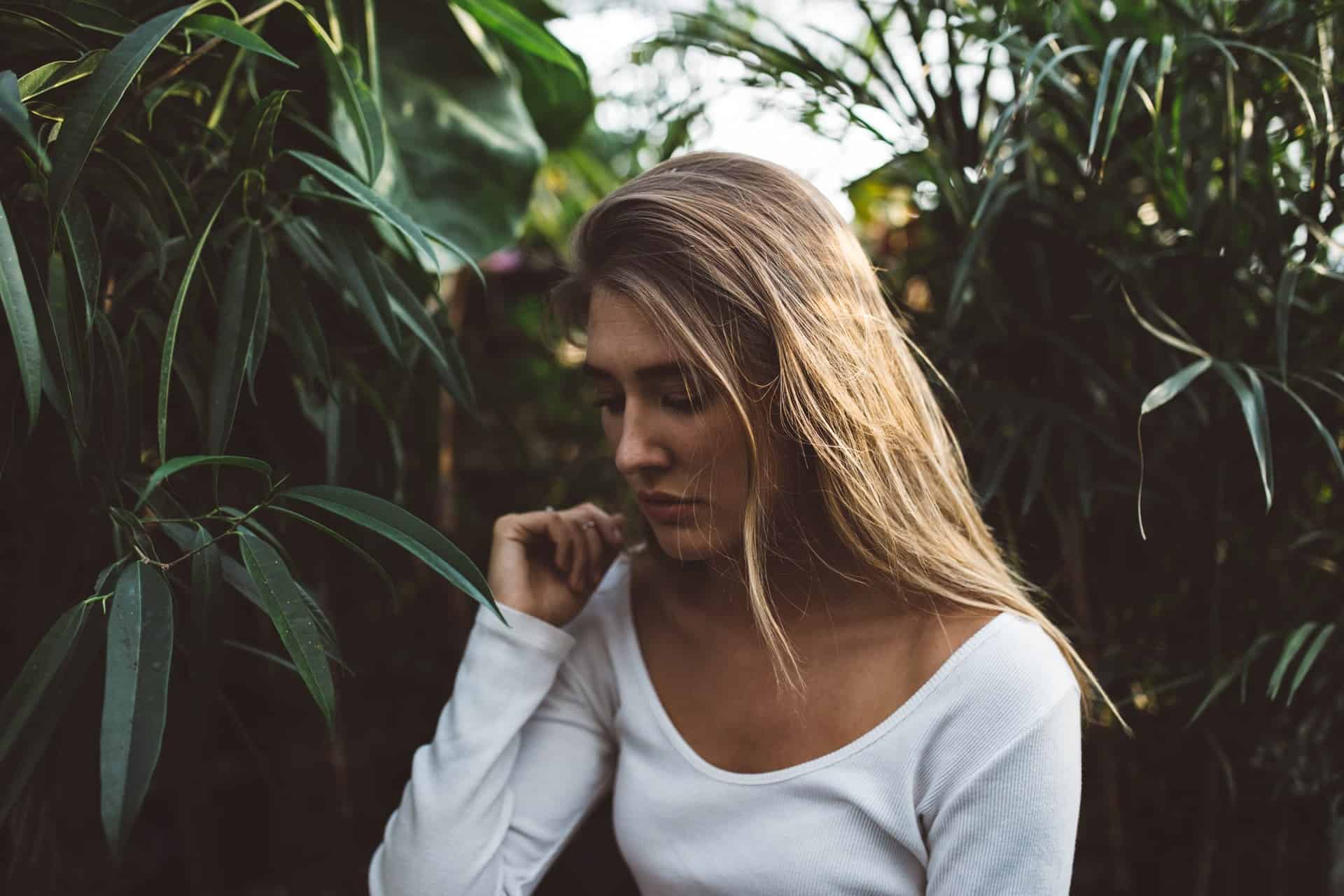 une femme aux cheveux blonds se tient à côté d'un saule