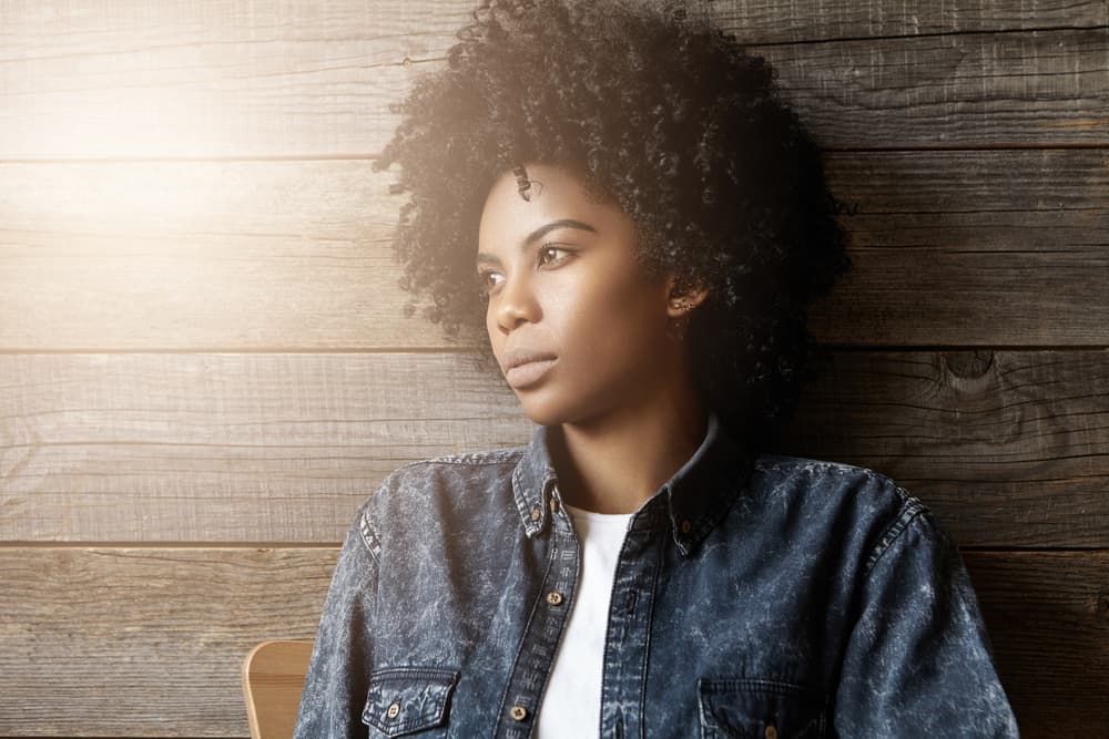 une femme aux cheveux crépus regarde ailleurs