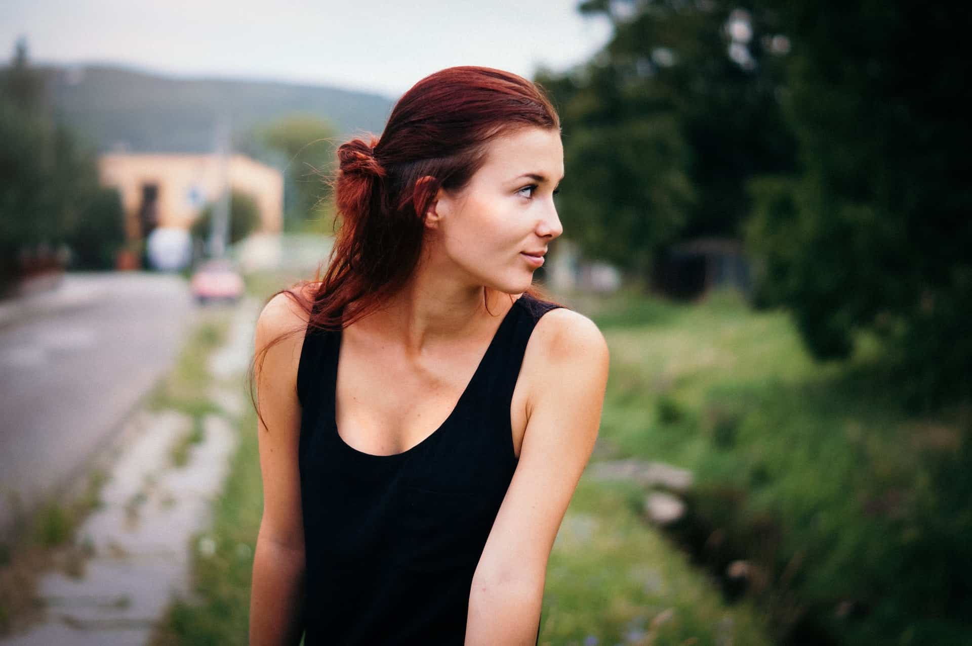 une femme aux cheveux rouges est assise sur une clôture