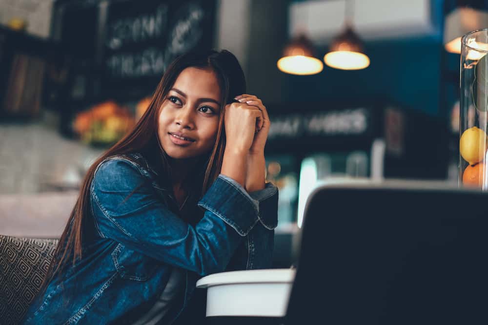 une femme aux longs cheveux noirs est assise seule à une table