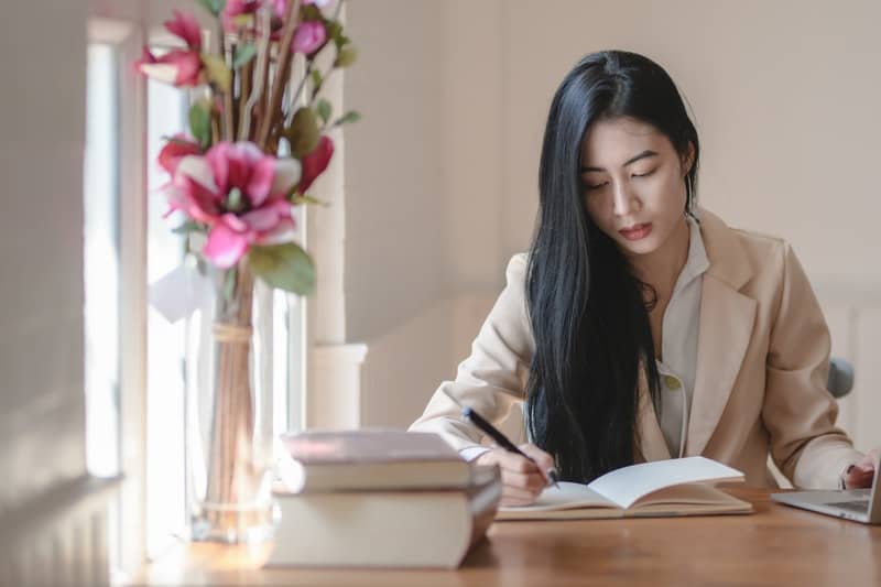 une femme aux longs cheveux noirs écrit une lettre imaginée