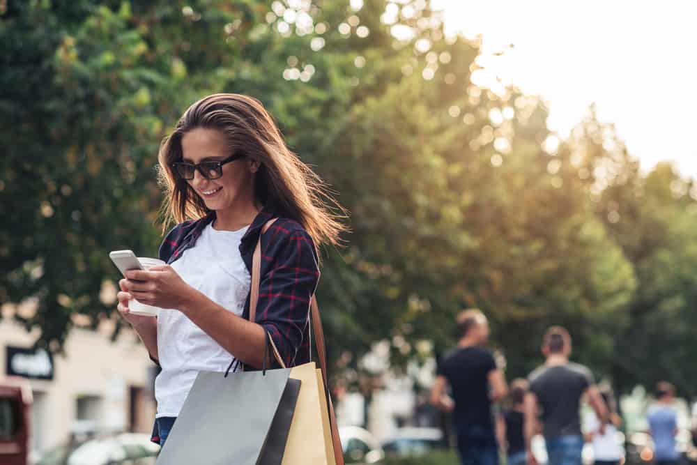 une femme avec des sacs marche dans la rue et un bouton sur le téléphone