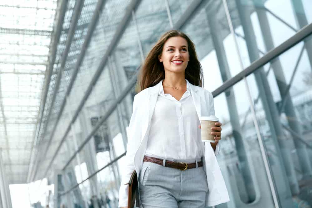 une femme avec du café à la main marche dans la rue