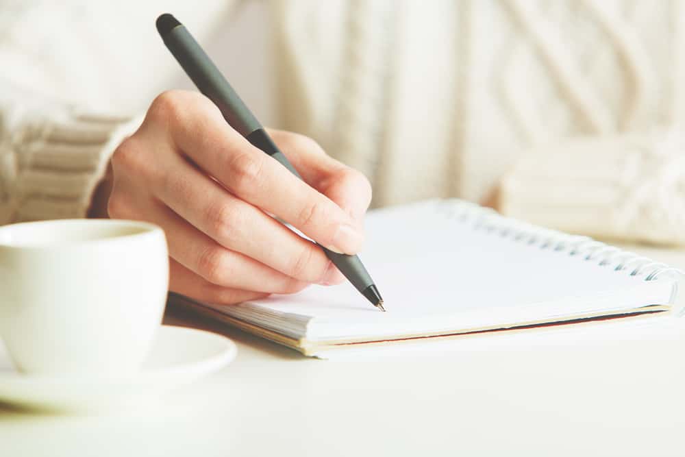 une femme avec du café écrit une lettre