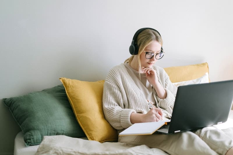 une femme avec un casque sur ses oreilles et un ordinateur portable écrit une lettre