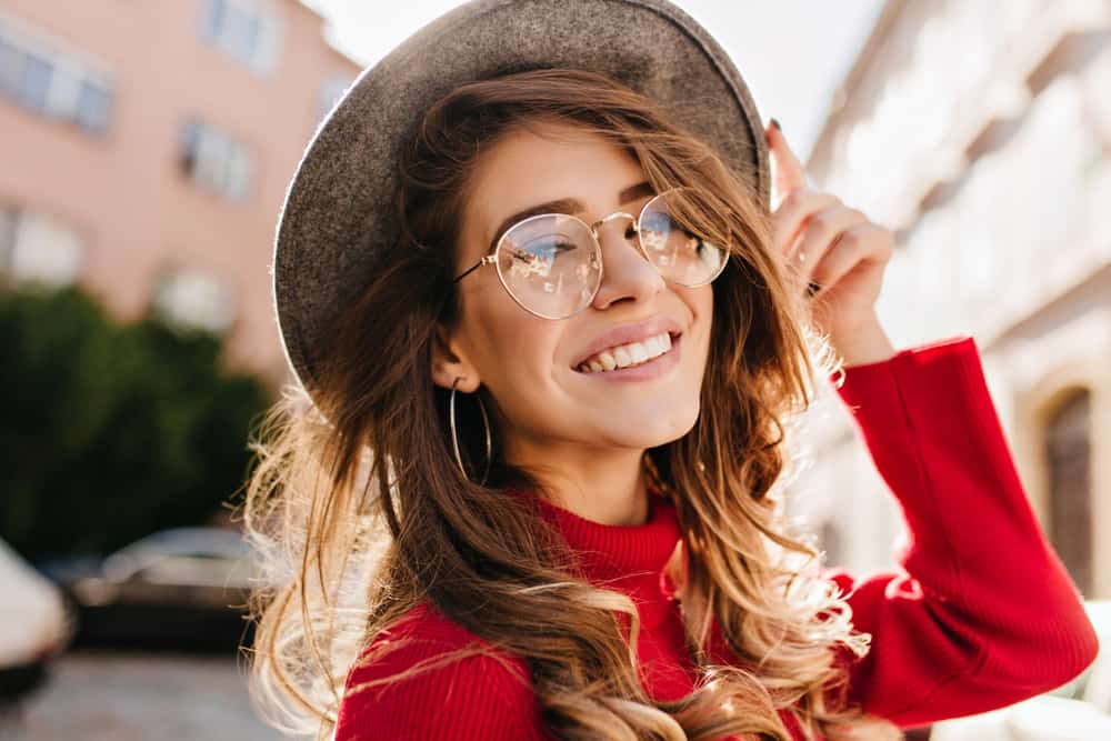 une femme avec un chapeau et des lunettes sur la tête rit