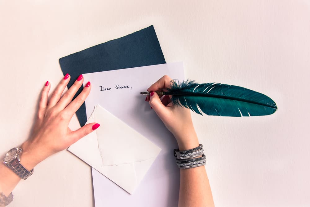 une femme avec un stylo écrit une carte de voeux