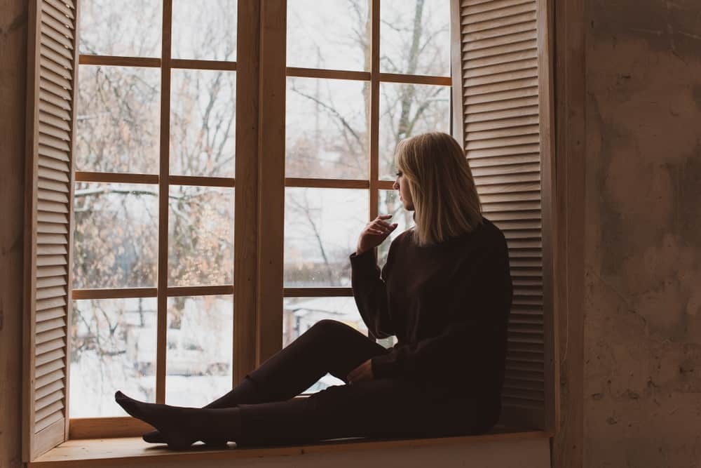 une femme blonde assise près de la fenêtre