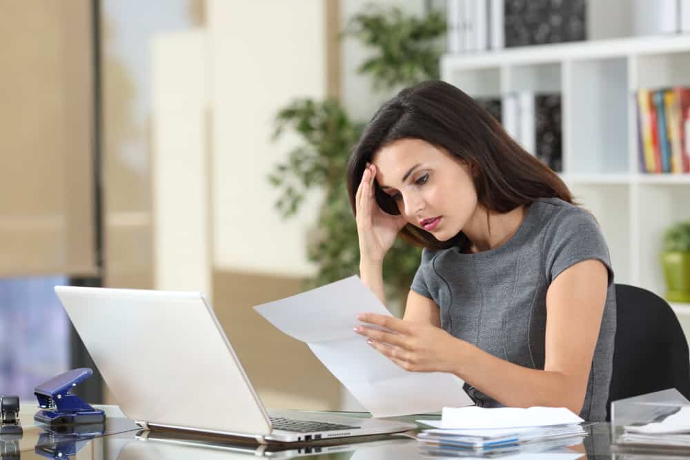 une femme confuse au travail est assise derrière un ordinateur portable