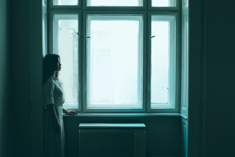 une femme déprimée debout près de la fenêtre