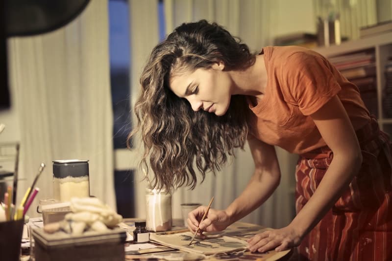 une femme dessine quelque chose à une table dans la maison