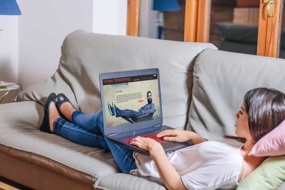 une femme est assise sur le canapé et un bouton sur l'ordinateur portable