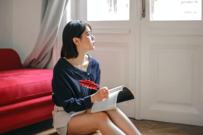 une femme est assise sur le sol et écrit